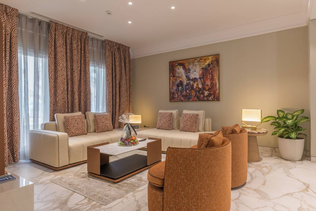 Ein stilvolles Wohnzimmer mit Sofa, Sesseln, einem Couchtisch und einem Gemälde an der Wand.