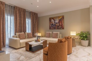 A modern living room with a sofa, armchairs, a coffee table, and a painting on the wall.