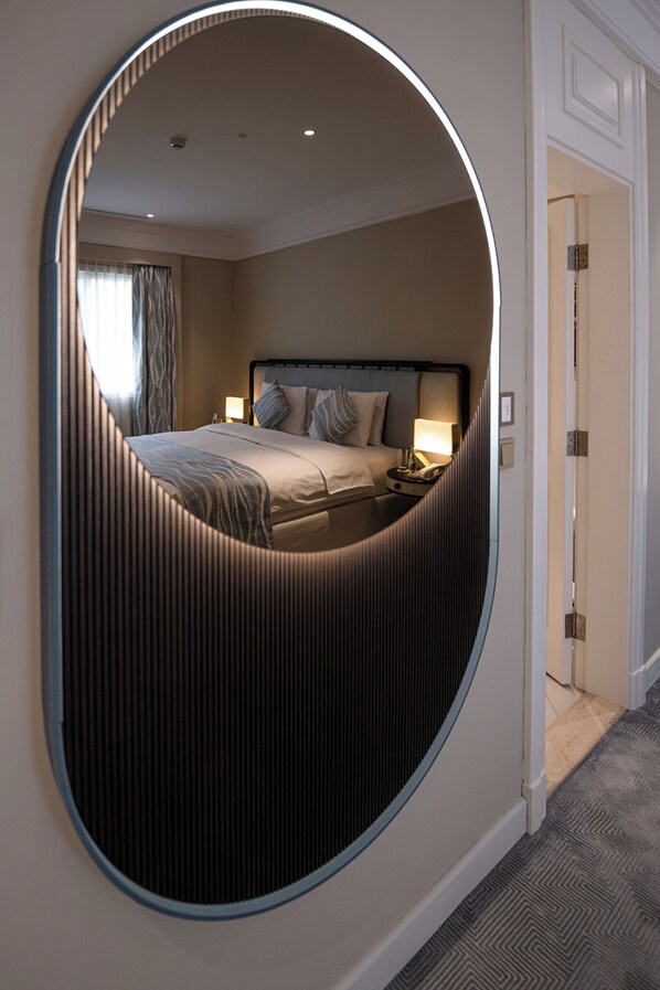 Une chambre d’hôtel avec un grand miroir, un lit avec des oreillers, une table de chevet et une lampe.