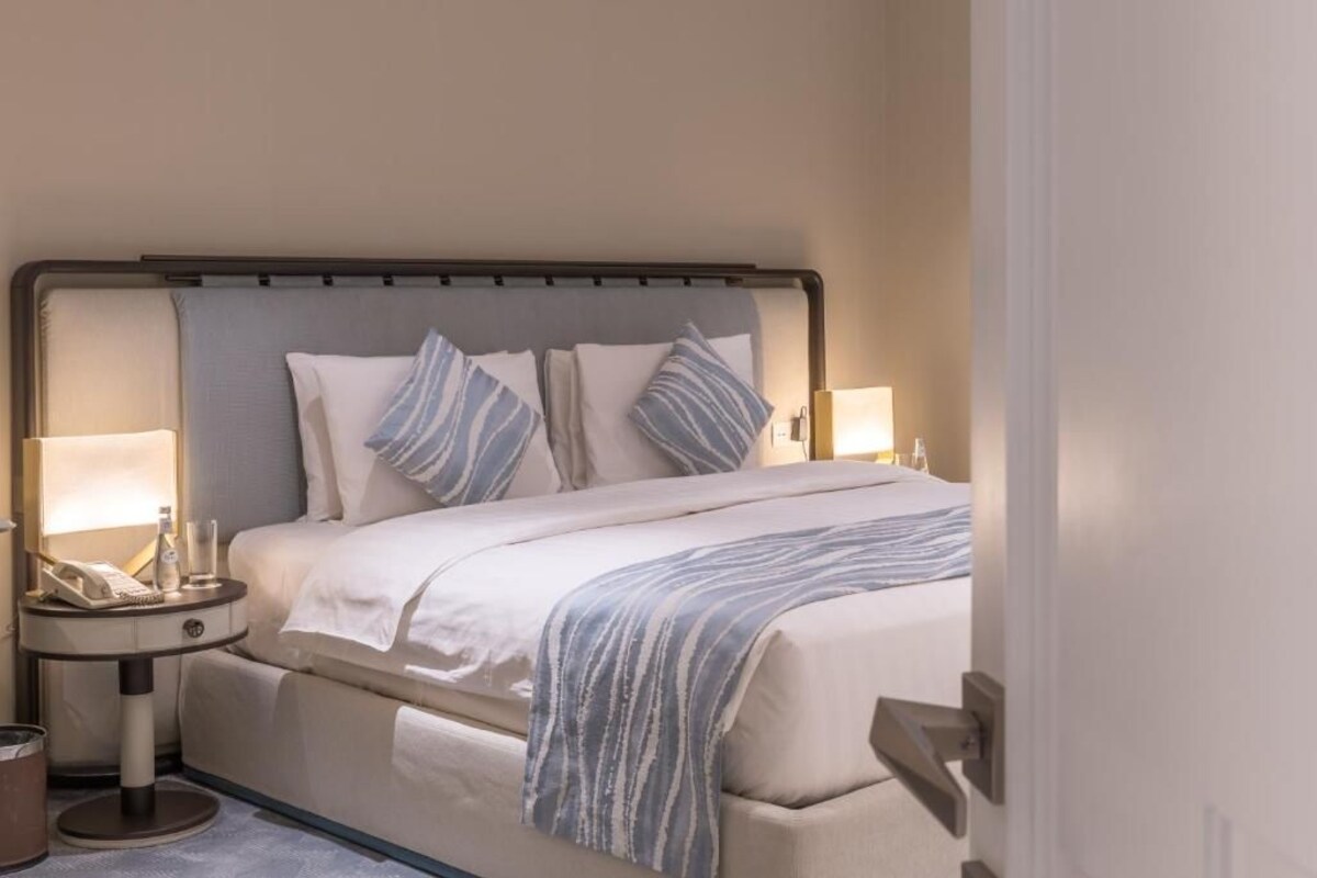 A hotel room with a bed, bedside lamps, a telephone, and a bedside table.