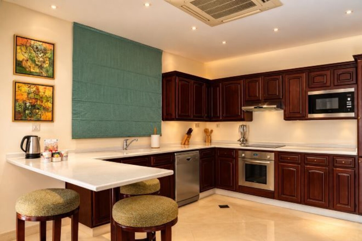A modern kitchen with dark wood cabinets, stainless steel appliances, and a white countertop.