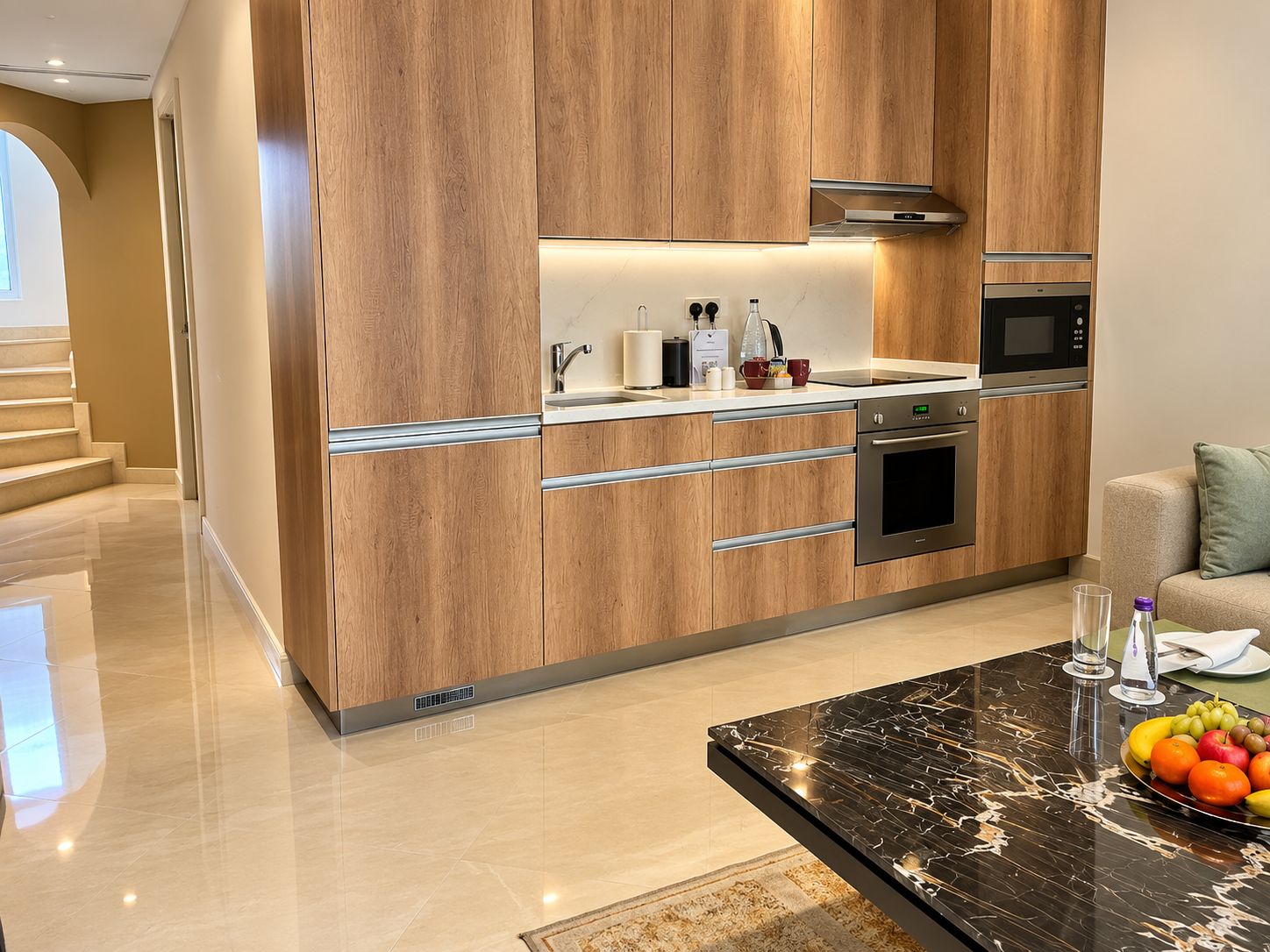 A modern kitchen with wooden cabinetry, stainless steel appliances, and a marble countertop.