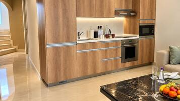 A modern kitchen with wooden cabinetry, stainless steel appliances, and a marble countertop.