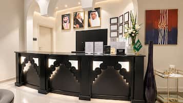 A reception desk with framed certificates, a reception sign, and a modern abstract painting.