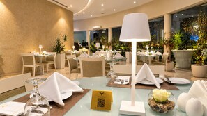 A well-lit dining area with tables set for service, a QR code for digital menu access, and a view of the outdoors through large windows. - Vivienda Hotel Villas, Turki Al Awwal (Riyadh)