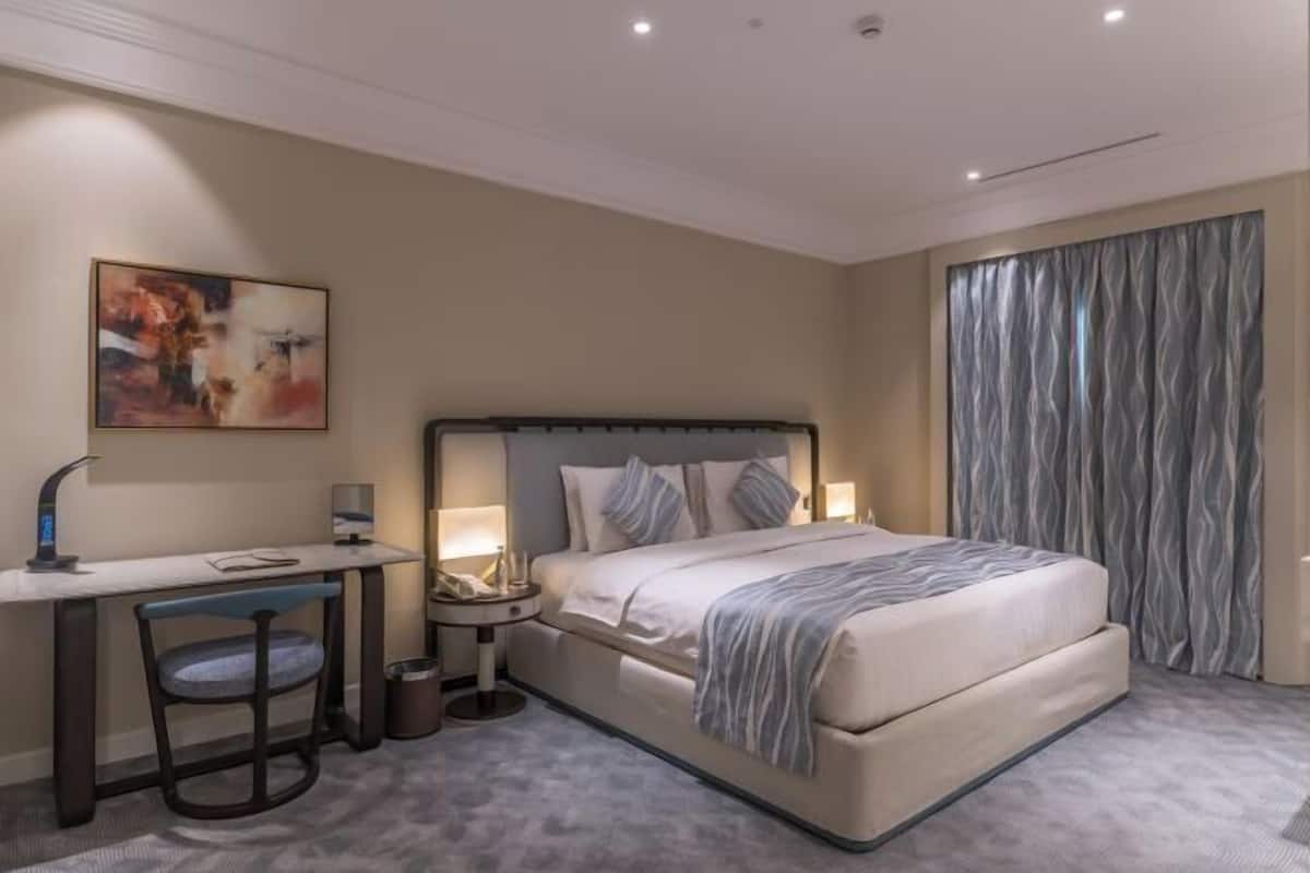 Ein Hotelzimmer mit Bett, Schreibtisch, Stuhl, Nachttischen und einem Bild an der Wand.