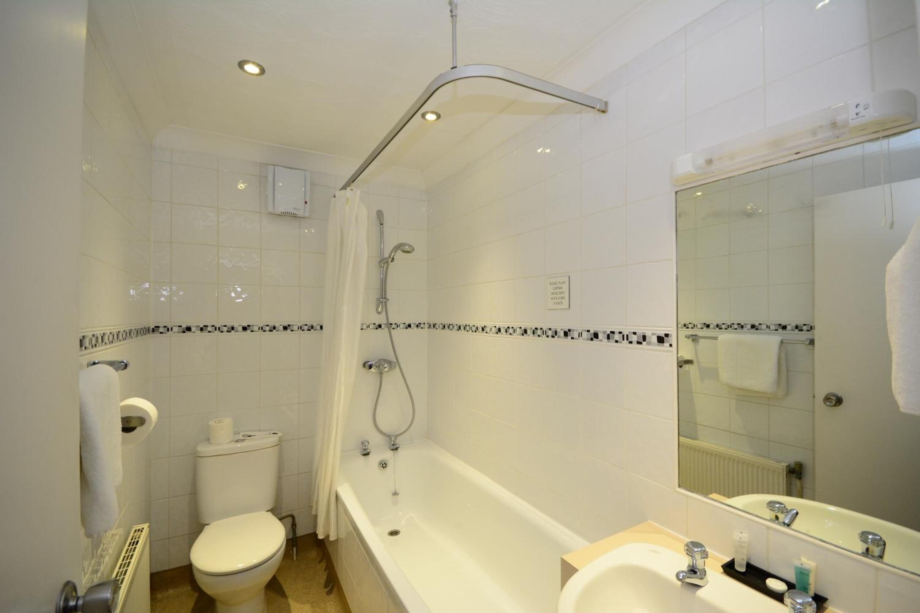 A bathroom with a toilet, bathtub, sink, and a mirror.