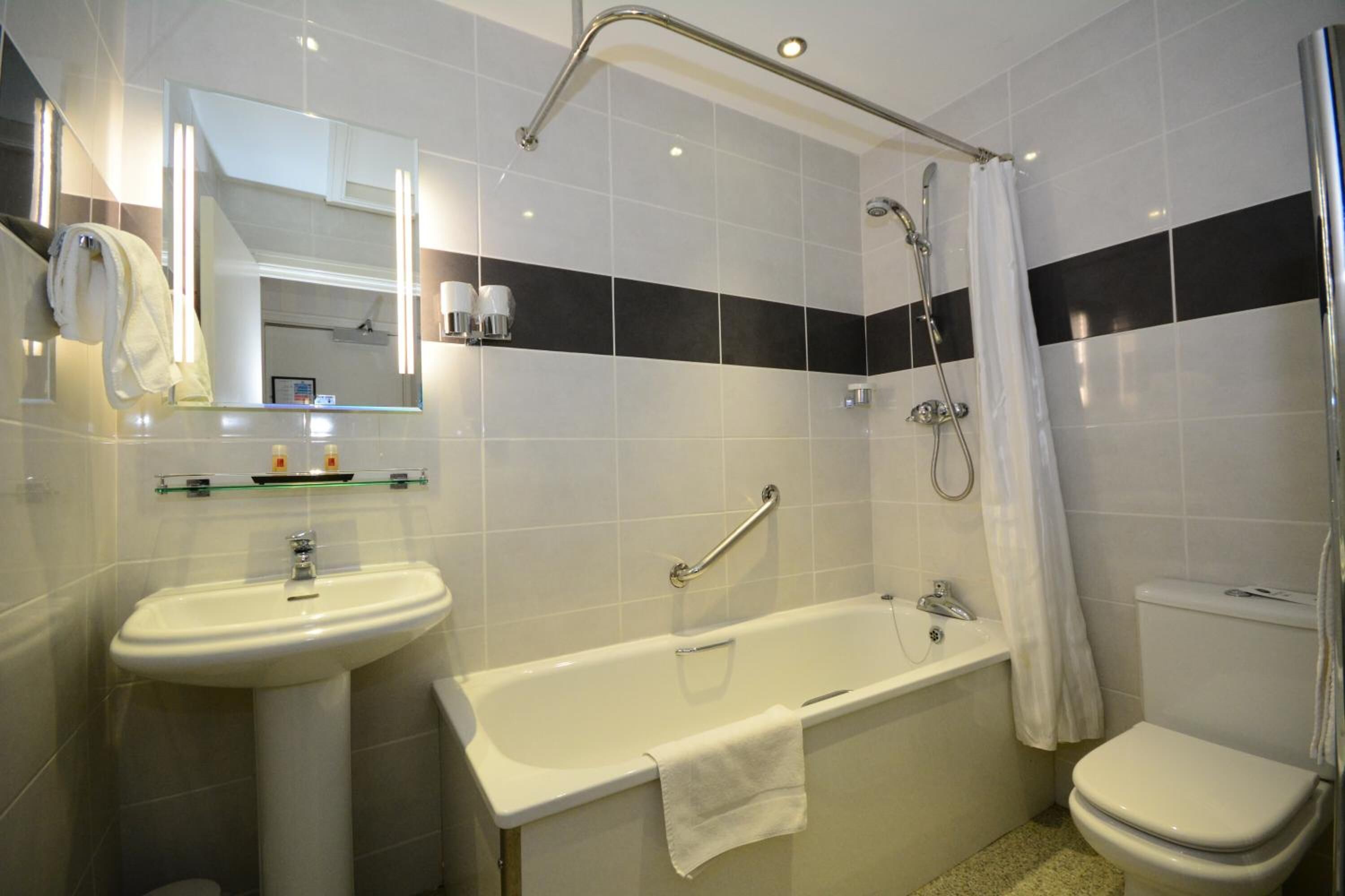 A modern bathroom with a sink, bathtub, and toilet.