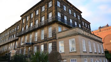 A historic building with multiple stories, named "Crescent Hotel." It features a classic architectural style with large windows and a balcony on the upper floors.