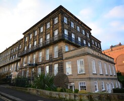 Un edificio histórico de varios pisos, llamado "Crescent Hotel". Presenta un estilo arquitectónico clásico con grandes ventanales y un balcón en los pisos superiores.