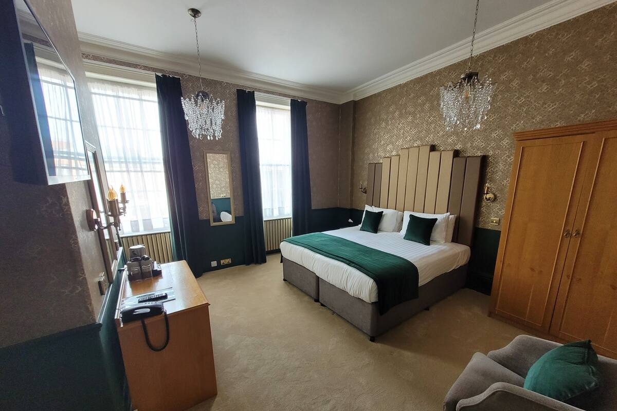 A hotel room with a bed, a desk, a chair, and a wardrobe.