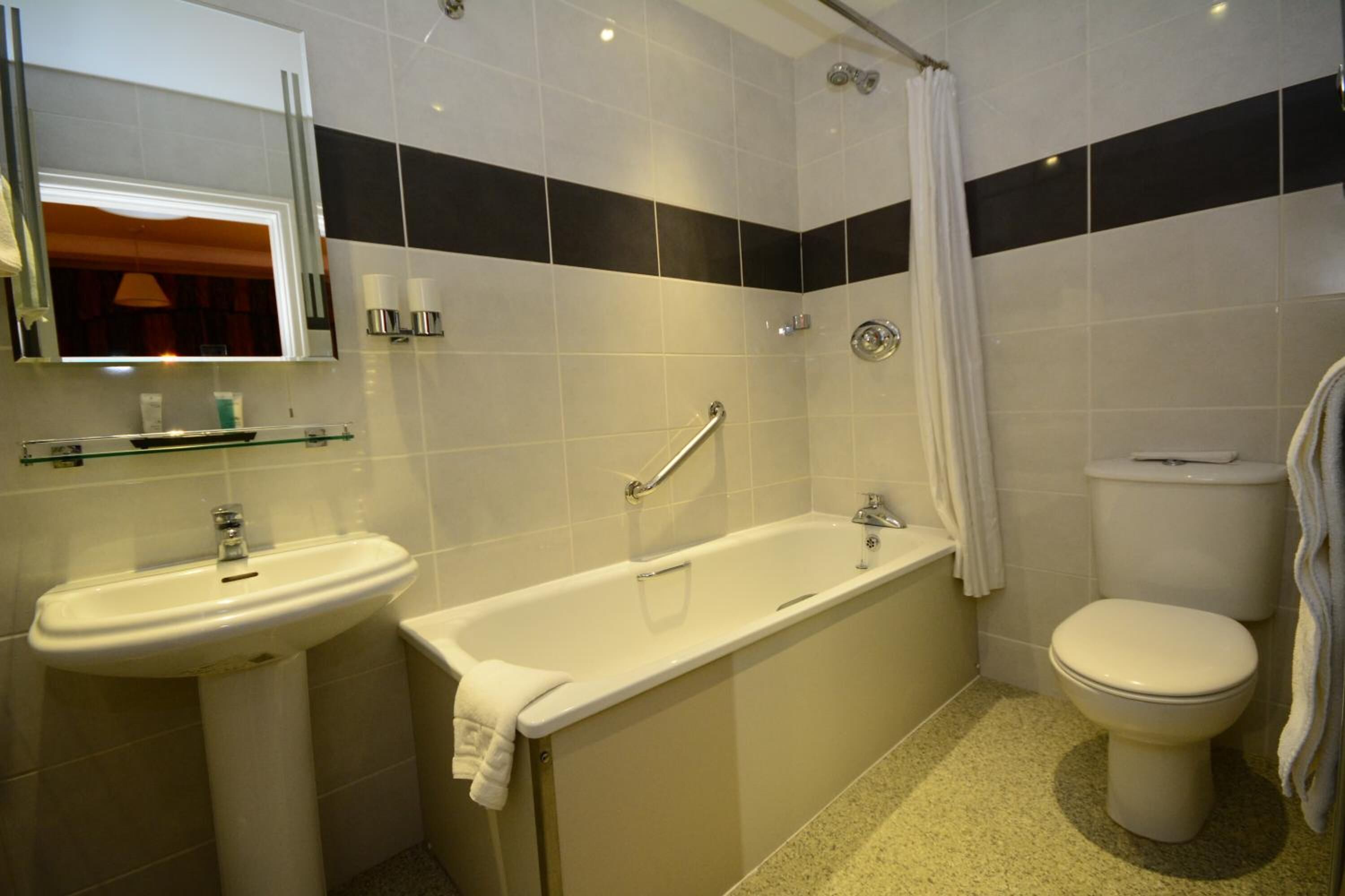 Un baño con lavamanos, bañera y retrete.