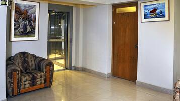 A lobby with a sofa, a wooden door, and two framed paintings.