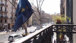 A street view with a flag, buildings, and a bridge. - Hostal Delfos (Barcelona)
