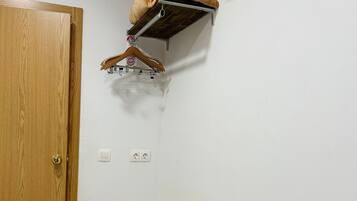 A room with a wooden door, a white radiator, a white toilet, and a hanging clothes rack.