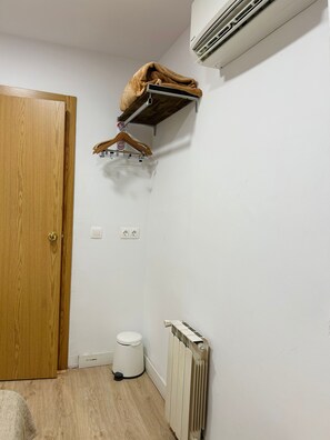 Een kamer met een houten deur, een witte radiator, een wit toilet en een kledingrek.