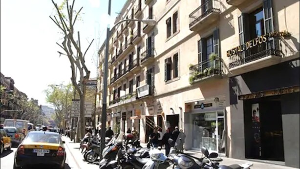A street with parked motorcycles and a taxi. - Hostal Delfos (Barcelona)