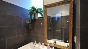 A bathroom with a large mirror, two sinks, a shower, and a potted plant. - The Posthoorn (Amsterdam)
