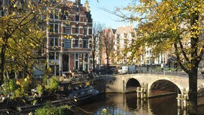 A canal with a stone bridge, buildings, and a boat. - The Posthoorn (Amsterdam)