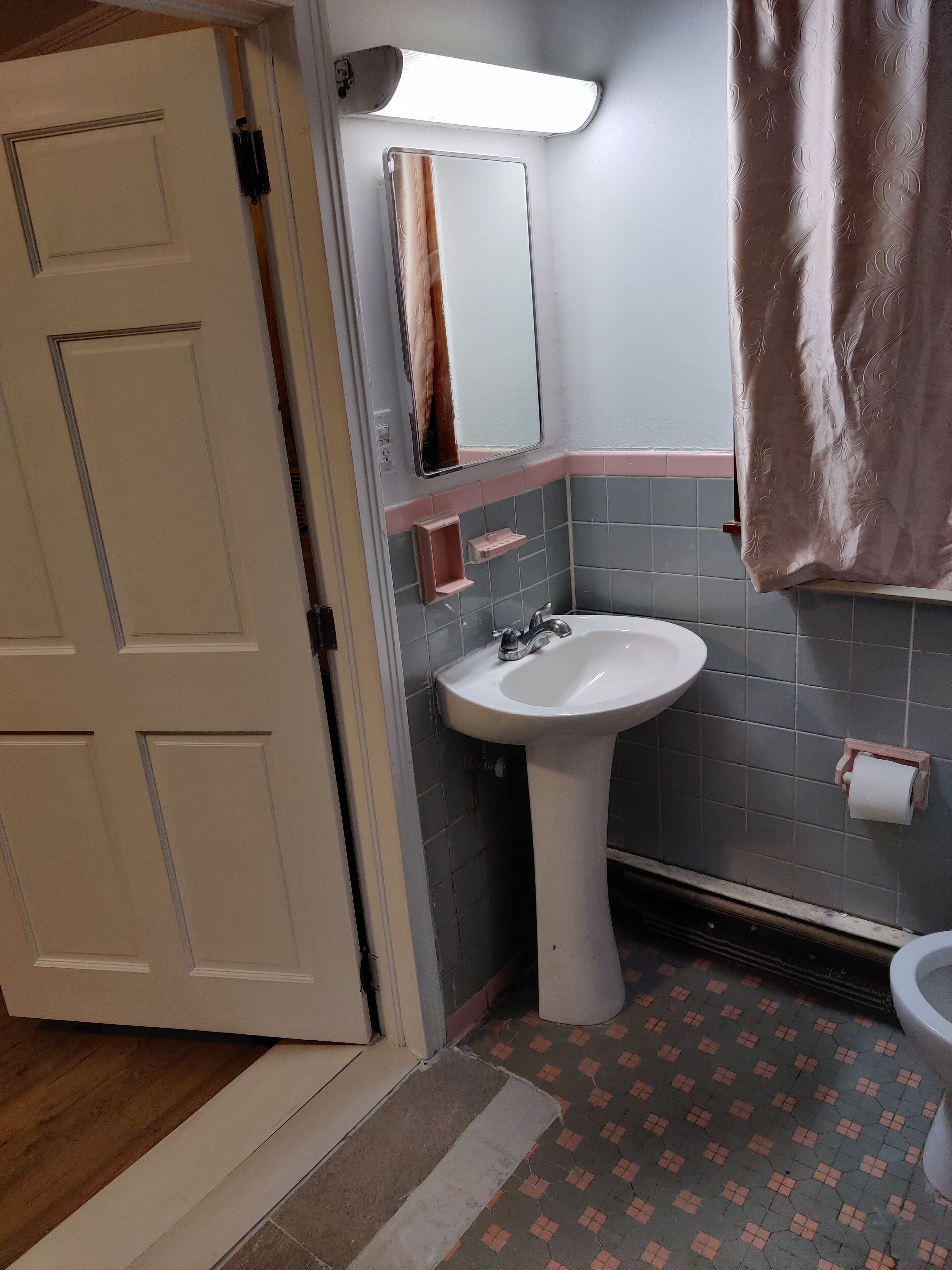 A bathroom with a white sink, a mirror, a towel hanging on the wall, and a toilet.