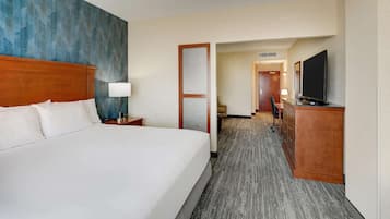 Une chambre d’hôtel avec un grand lit, un bureau doté d’un téléviseur à écran plat, une commode et un sol recouvert de moquette.