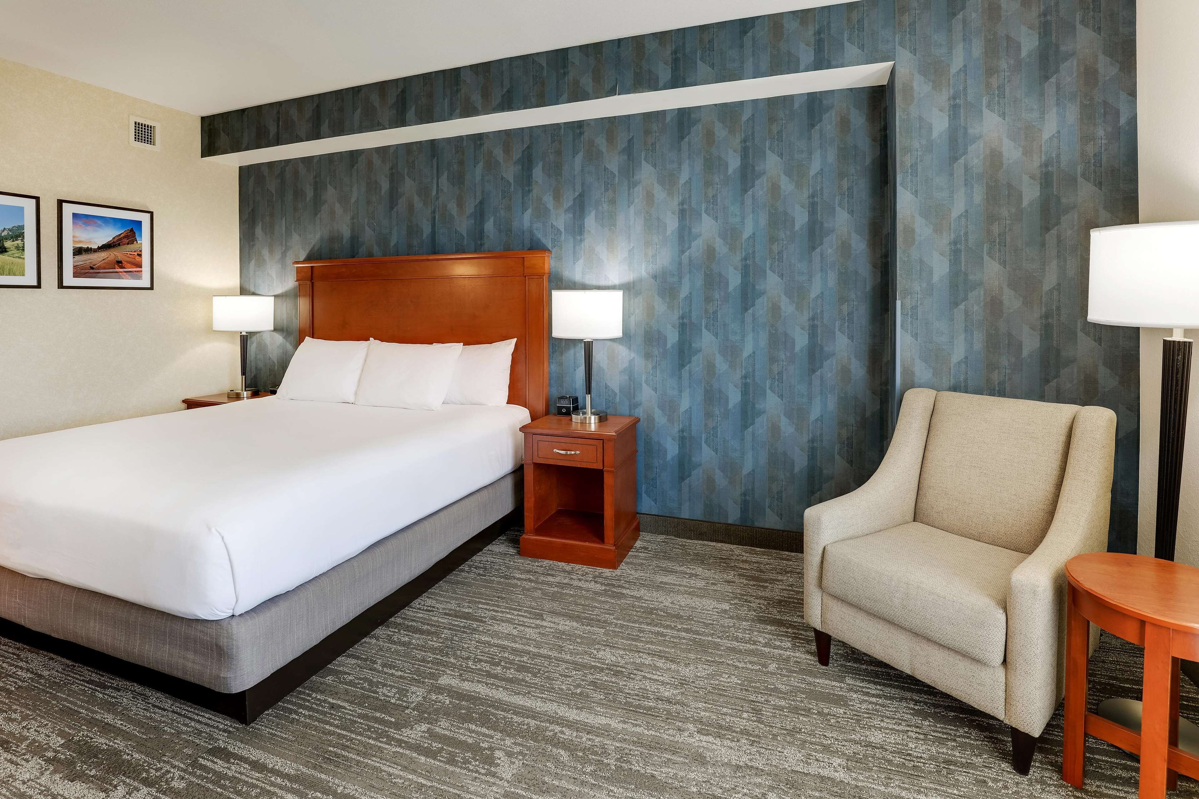 A hotel room with a large bed, two bedside tables with lamps, a chair, and a small table.