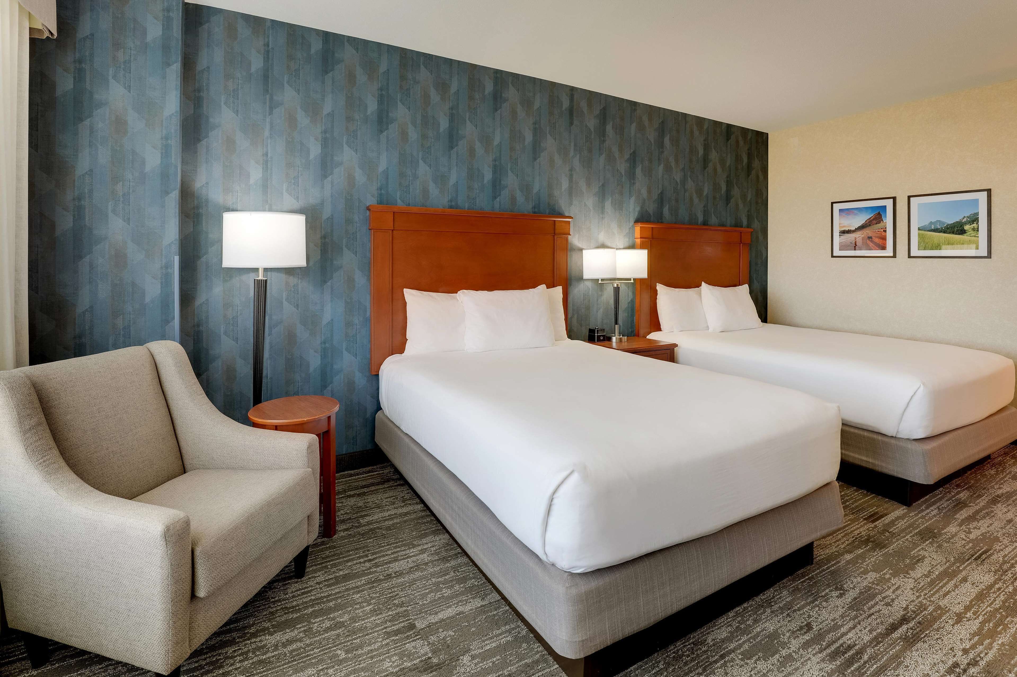 A hotel room with two beds, a sofa, and a lamp.