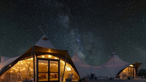 A series of dome-shaped tents with illuminated interiors, set against a starry night sky. - Under Canvas West Yellowstone (West Yellowstone)