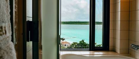 A bathroom with a bathtub and a view of a body of water through a window.