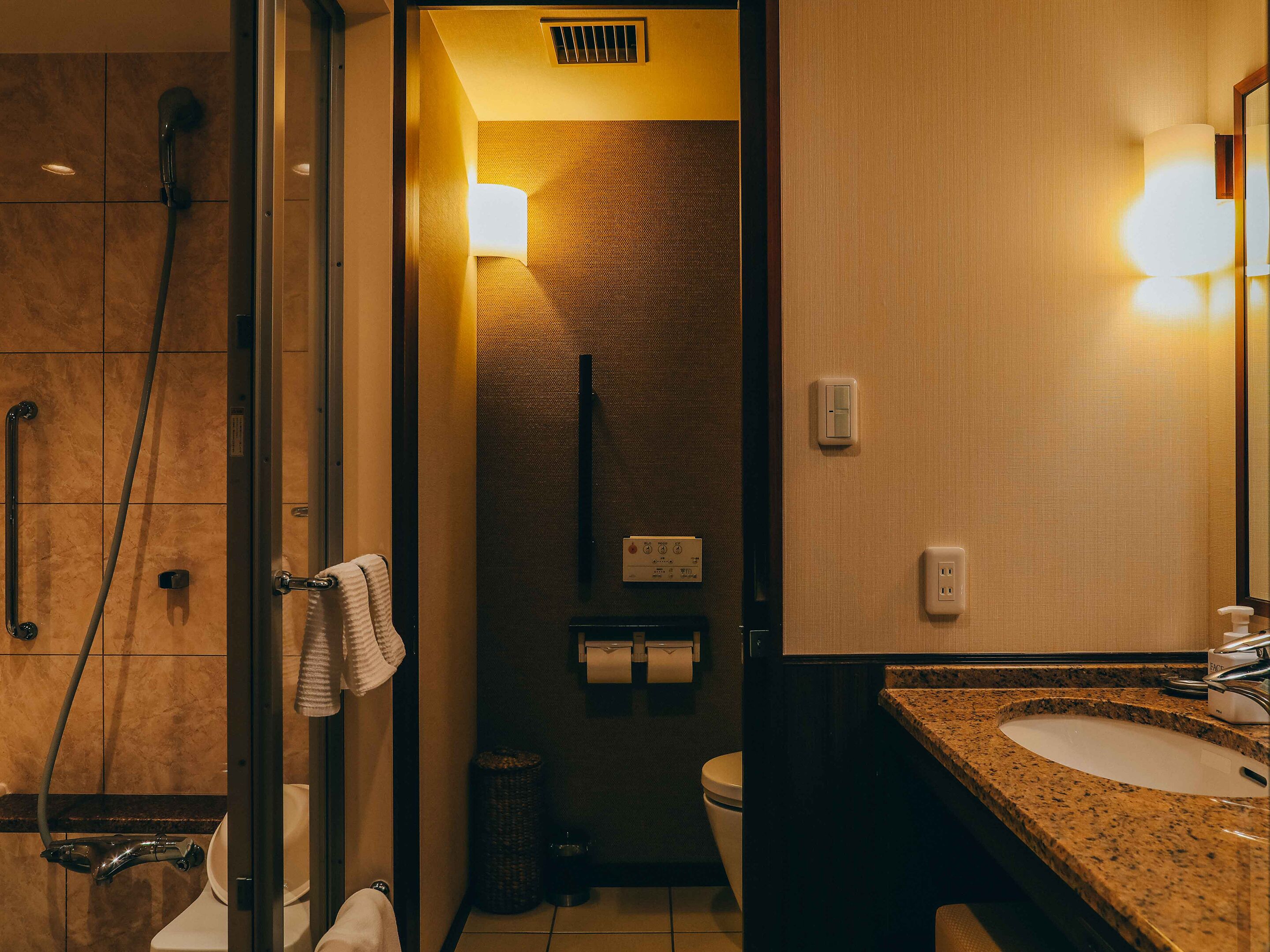 Un baño de hotel con ducha, inodoro y lavamanos.
