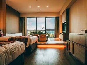 Une chambre d’hôtel avec deux lits, une télévision, un balcon donnant sur la plage et un bureau avec une chaise.