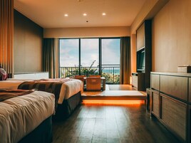 A hotel room with two beds, a TV, a balcony with a view of the beach, and a desk with a chair.