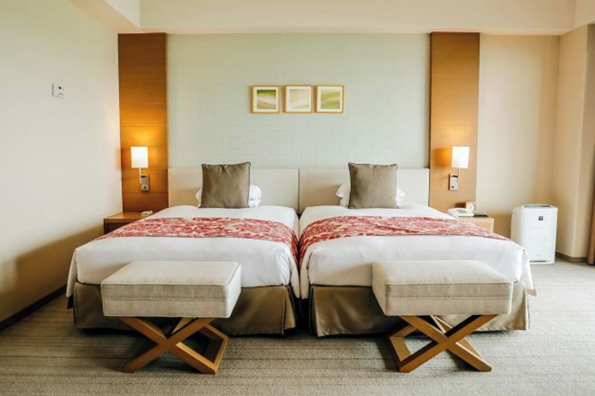 A double room with two beds, bedside tables, lamps, and a small bedside heater.