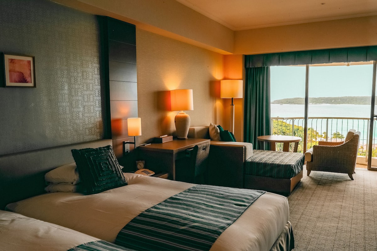 Habitación de hotel con una cama grande, un escritorio, una silla y vistas al mar.