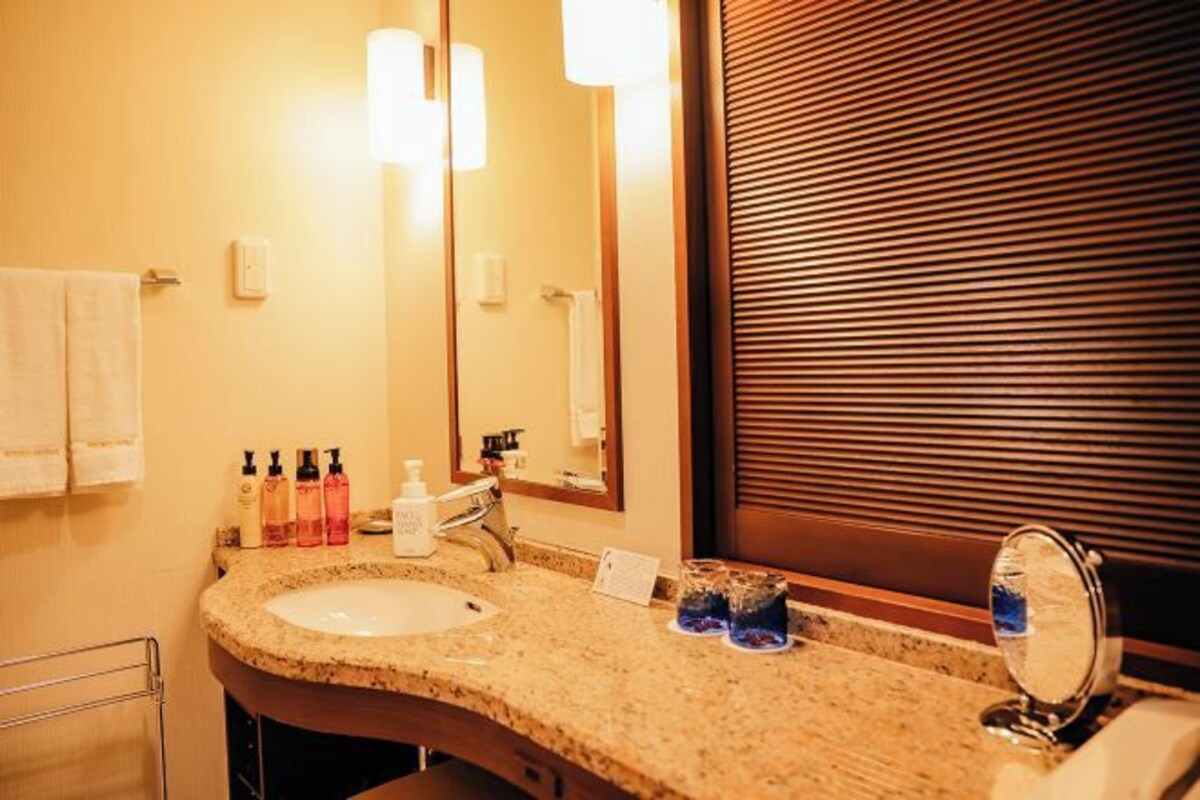 A bathroom with a granite countertop sink, a mirror, and a towel rack.