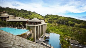 Un resort con una gran piscina, varias zonas de descanso y abundante vegetación alrededor de la propiedad.