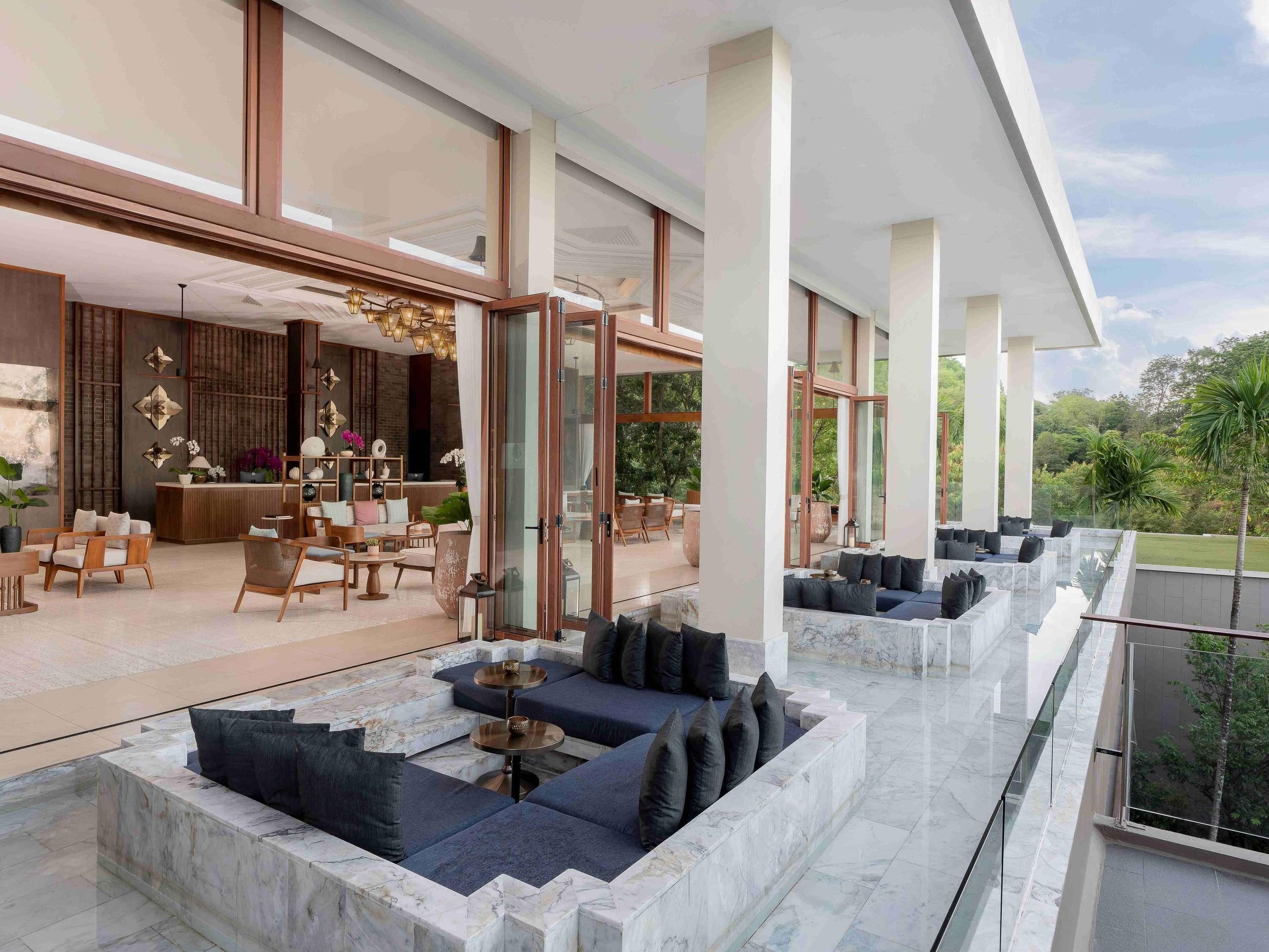 Un espacio interior amplio con arreglos de asientos, una recepción y ventanas grandes que dan a vistas del exterior.
