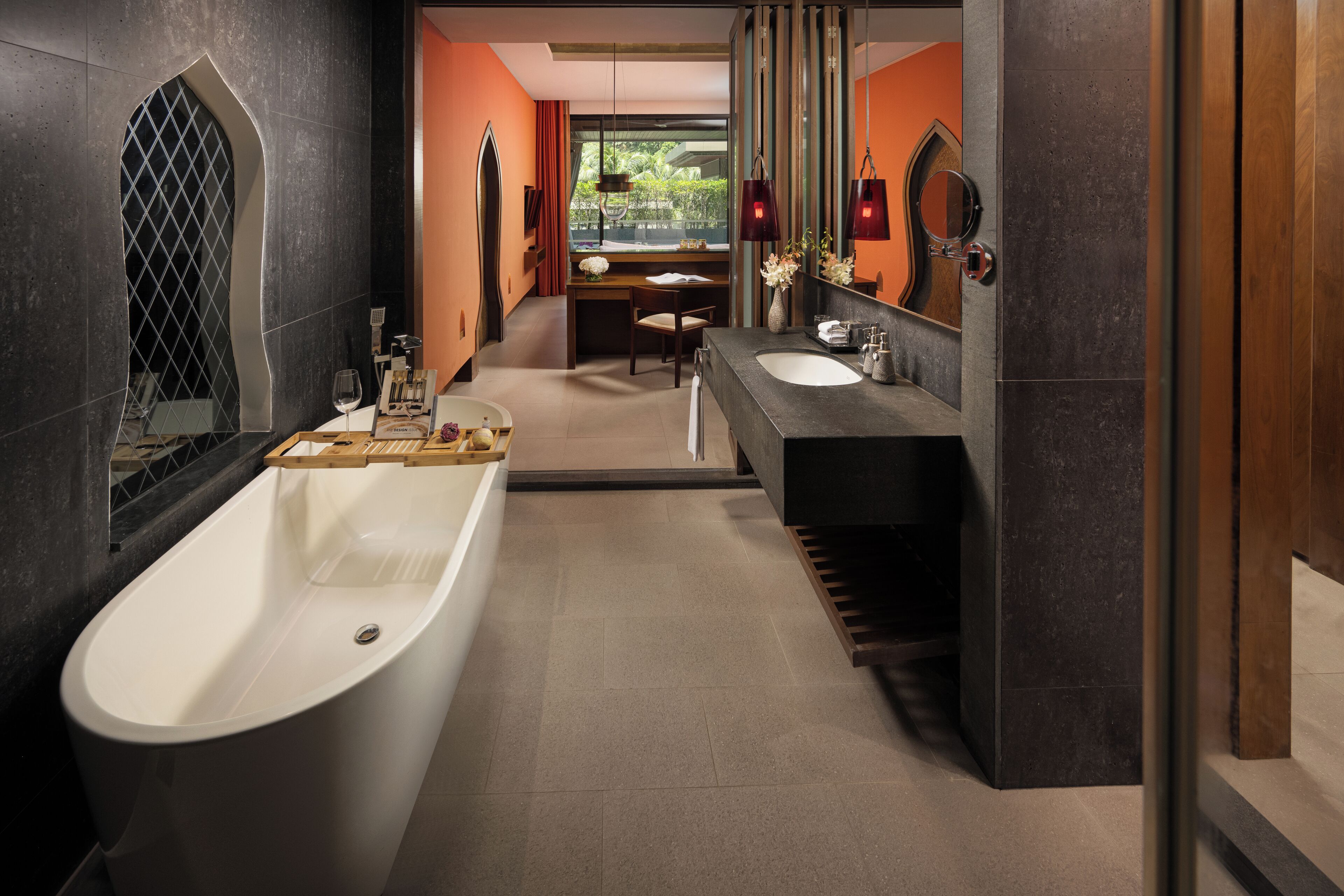 Un baño moderno con una bañera independiente, un tocador con espejo y una ventana con vistas al exterior.