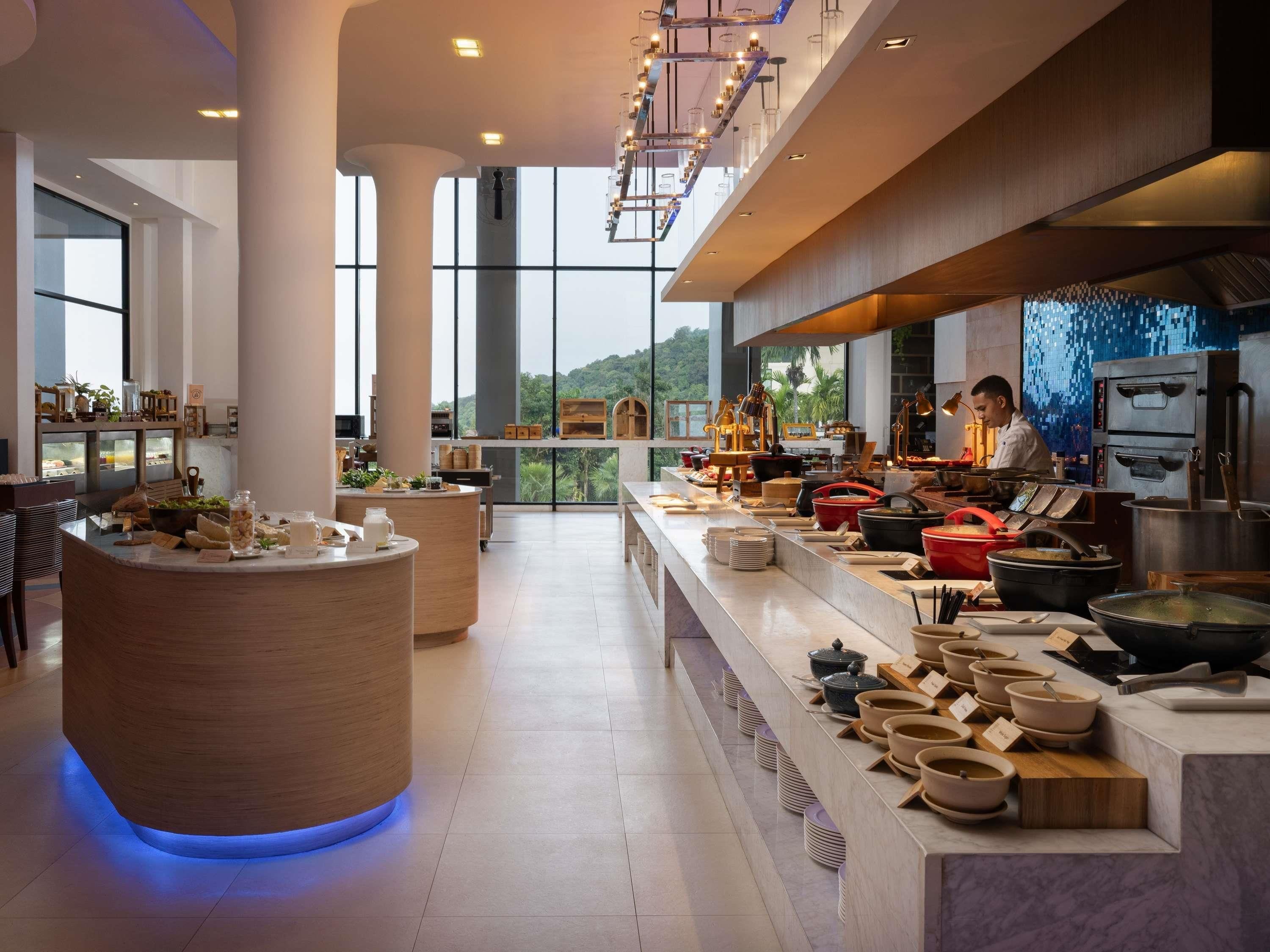 Una cocina de hotel moderna con una barra libre, ventanas amplias y vistas al exterior.