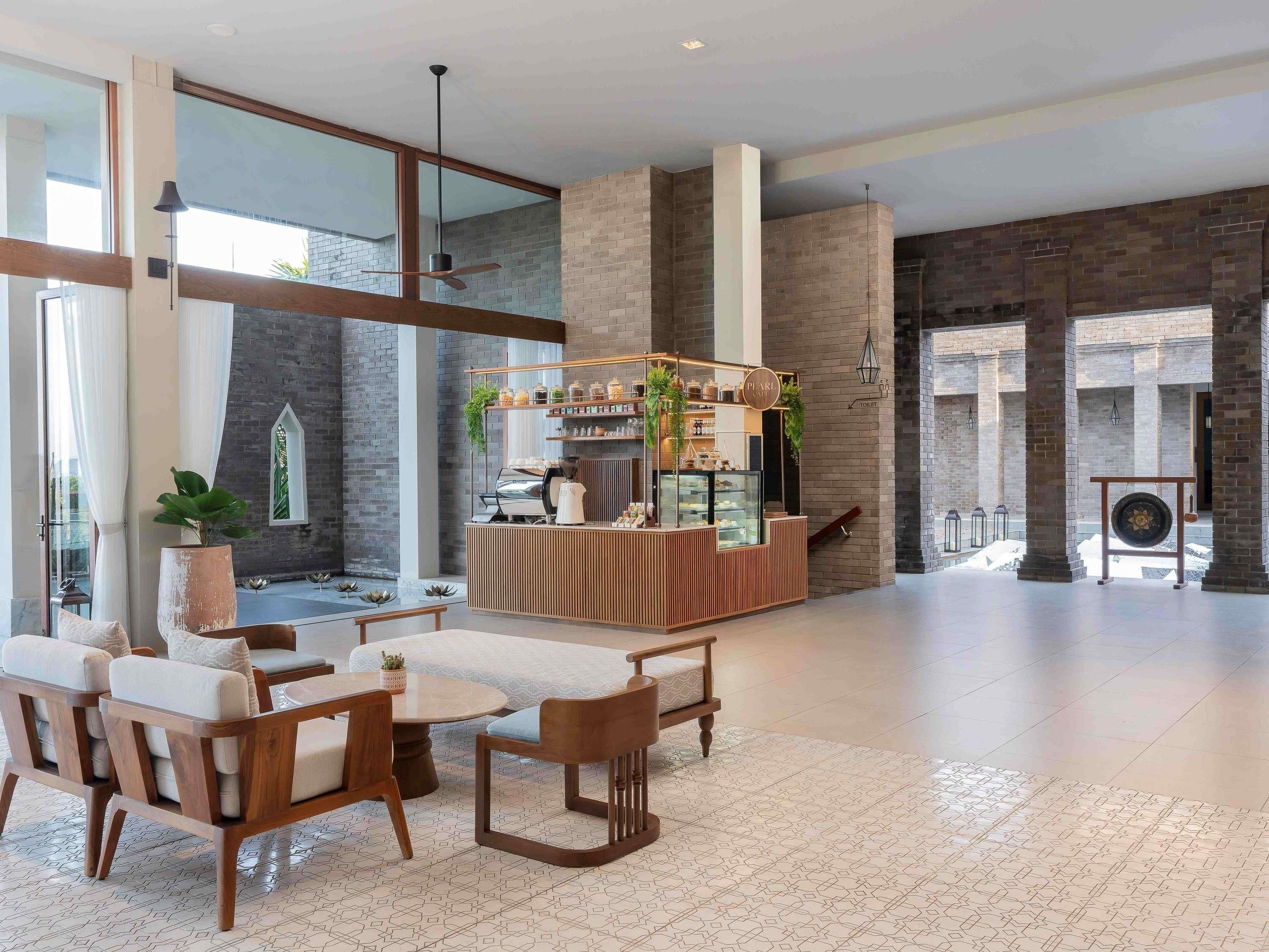 A modern interior with a seating area, a counter with a coffee machine, and a view of a courtyard.