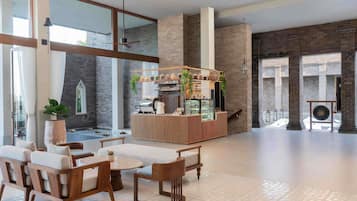 A modern interior with a seating area, a counter with a coffee machine, and a view of a courtyard.
