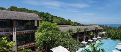 A resort with a pool, outdoor seating, and a view of the ocean.