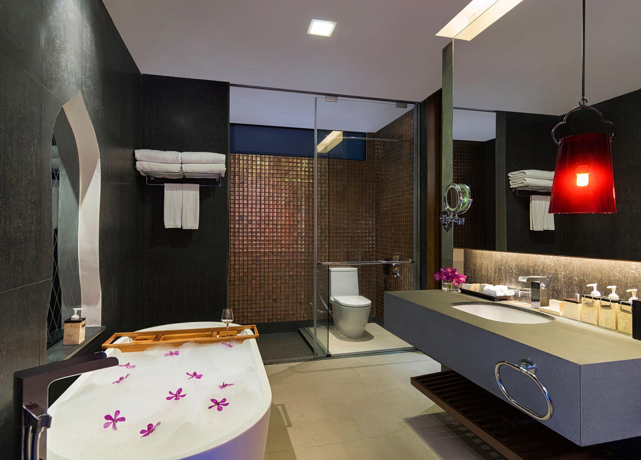 Un baño moderno con bañera, inodoro y tocador con espejo.