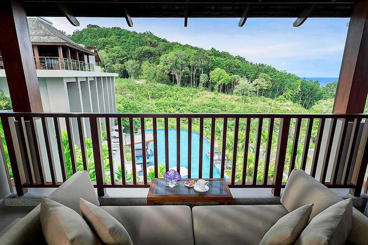 A balcony with a view of a pool and lush greenery.