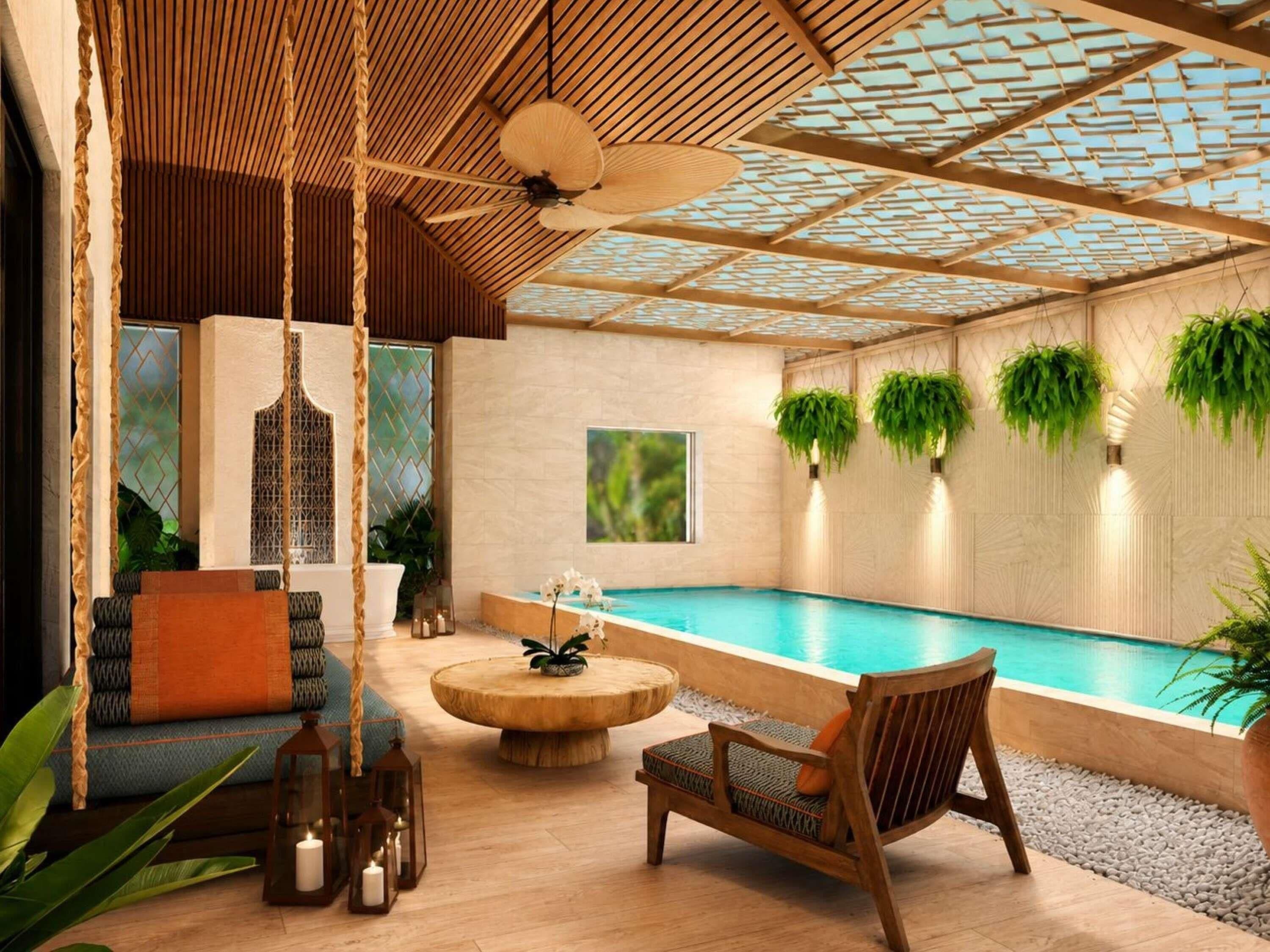 A pool area with a wooden ceiling, a seating area with a round table, and hanging plants.