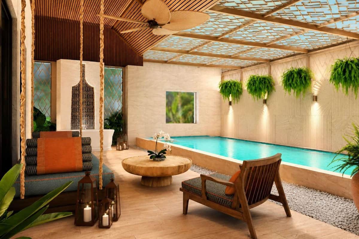 A pool area with a wooden ceiling, a seating area with a round table, and hanging plants.