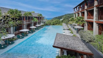 Un hotel con piscina, sillas de descanso y sombrillas.