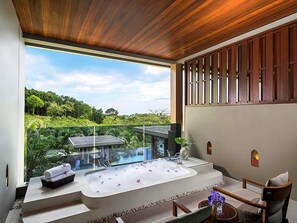 Un baño moderno con una bañera grande, una ducha con cerramiento de vidrio y vistas a un paisaje exuberante.