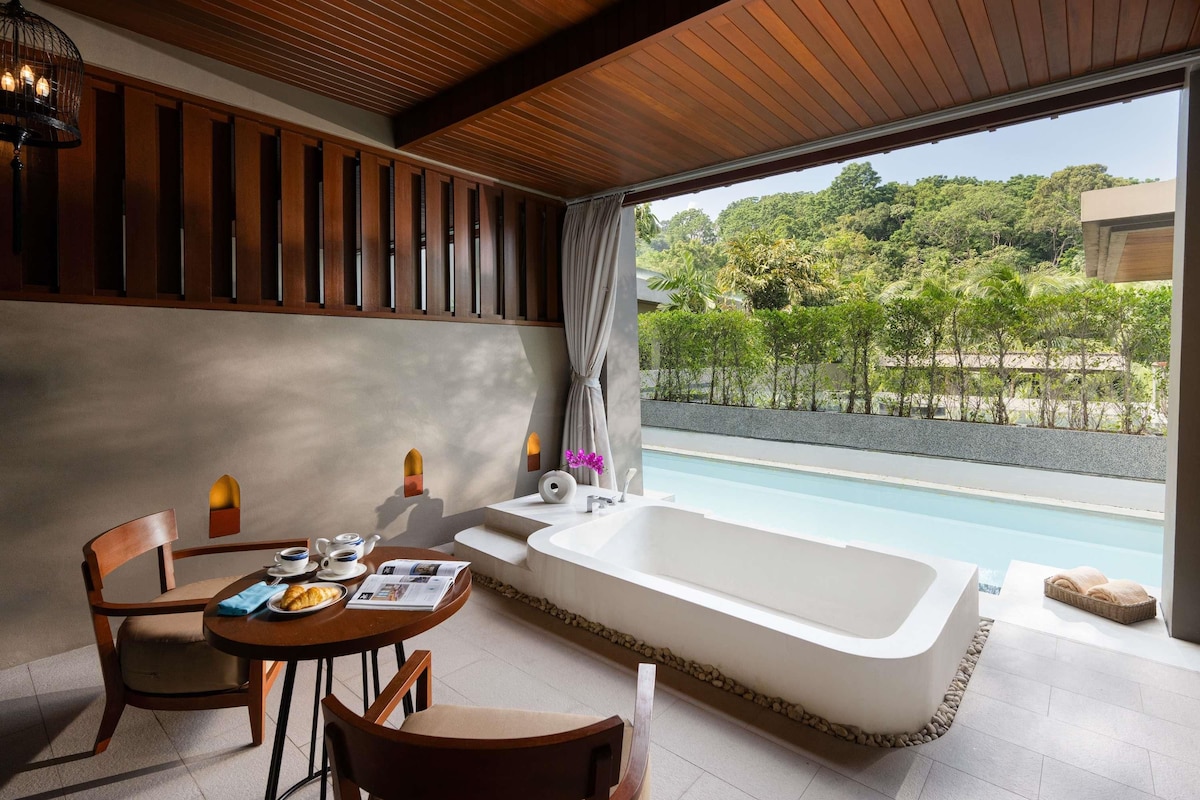 Un bany modern amb una banyera gran, un lavabo i una finestra amb vista a una piscina.