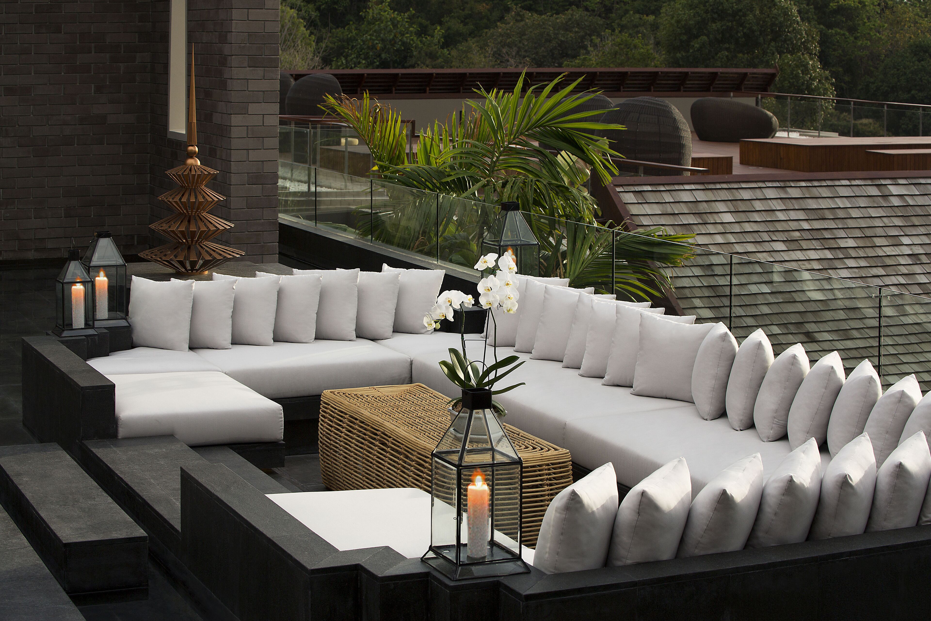 A modern outdoor seating area with a sectional sofa, cushions, and a lantern.